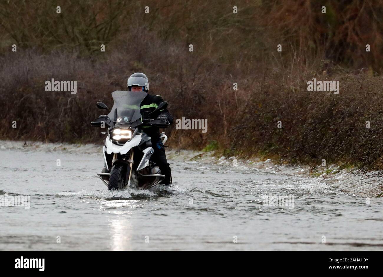 A motorcyclist tries to ride down a flooded road near Harbridge, 2.5 miles north of Ringwood in Hampshire, after the river Avon burst its banks. Stock Photo