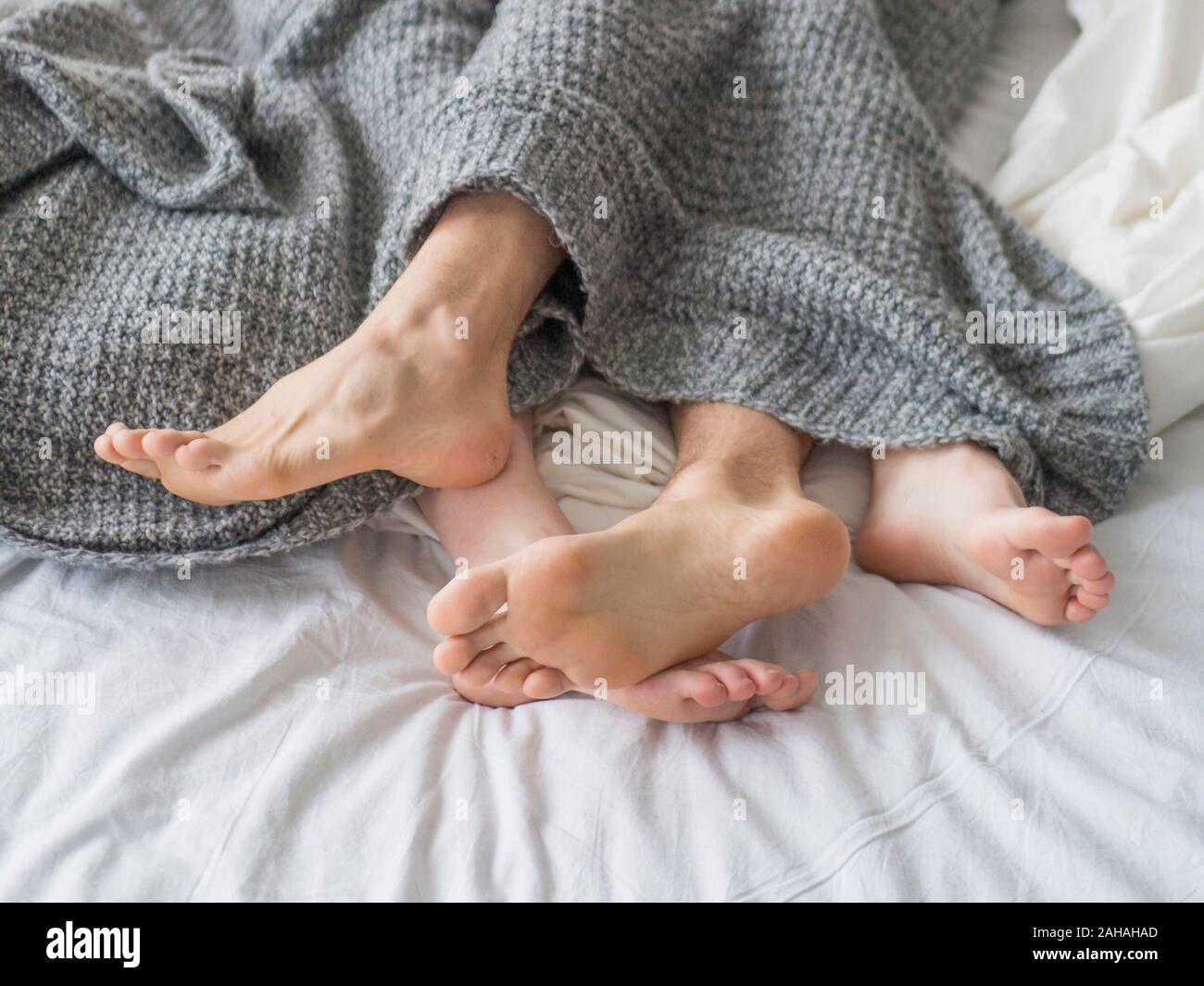 Passionate love. Feet of a young couple that lying on the bed at honeymoon. Couple in love sleeping under blanket. Concept : love, sweetheart, sweet, Stock Photo