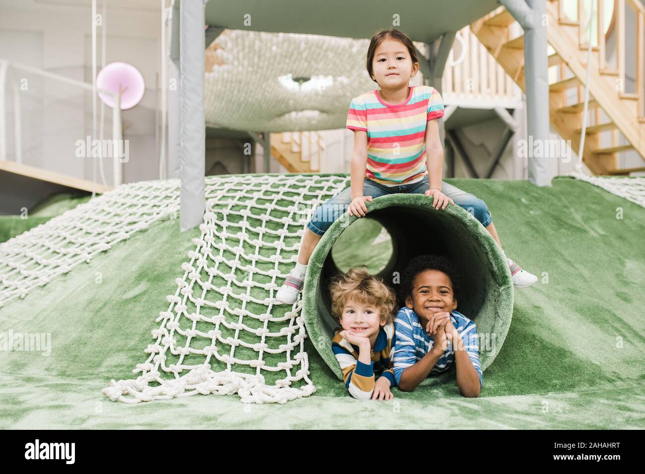 Cheerful and friendly intercultural little kids having fun together on play area Stock Photo