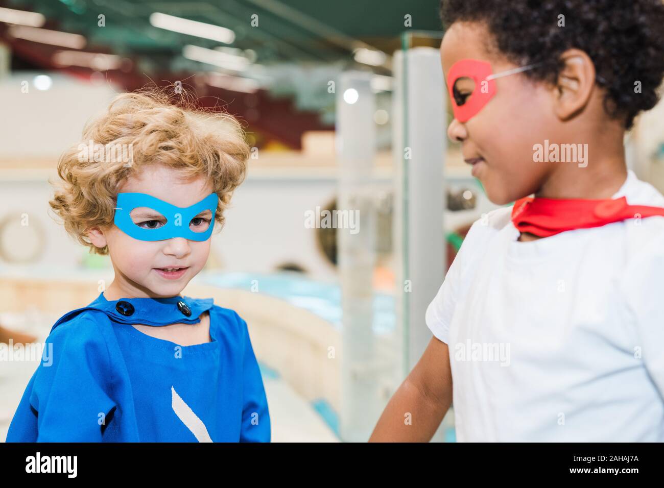 Two little boys wearing costumes of superheroes playing together in kindergarten Stock Photo