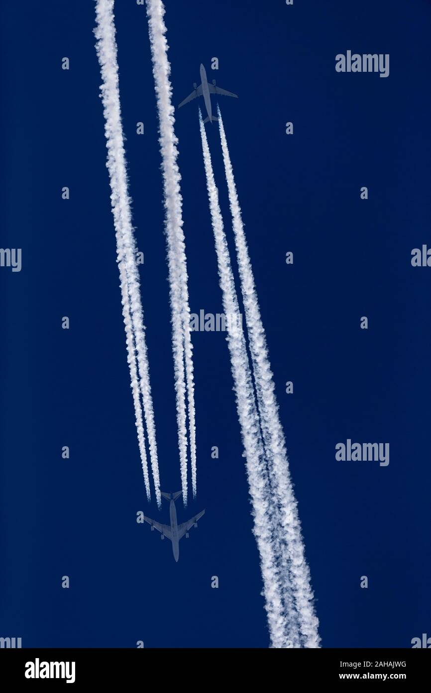 Two airplanes with contrails in the blue sky Stock Photo