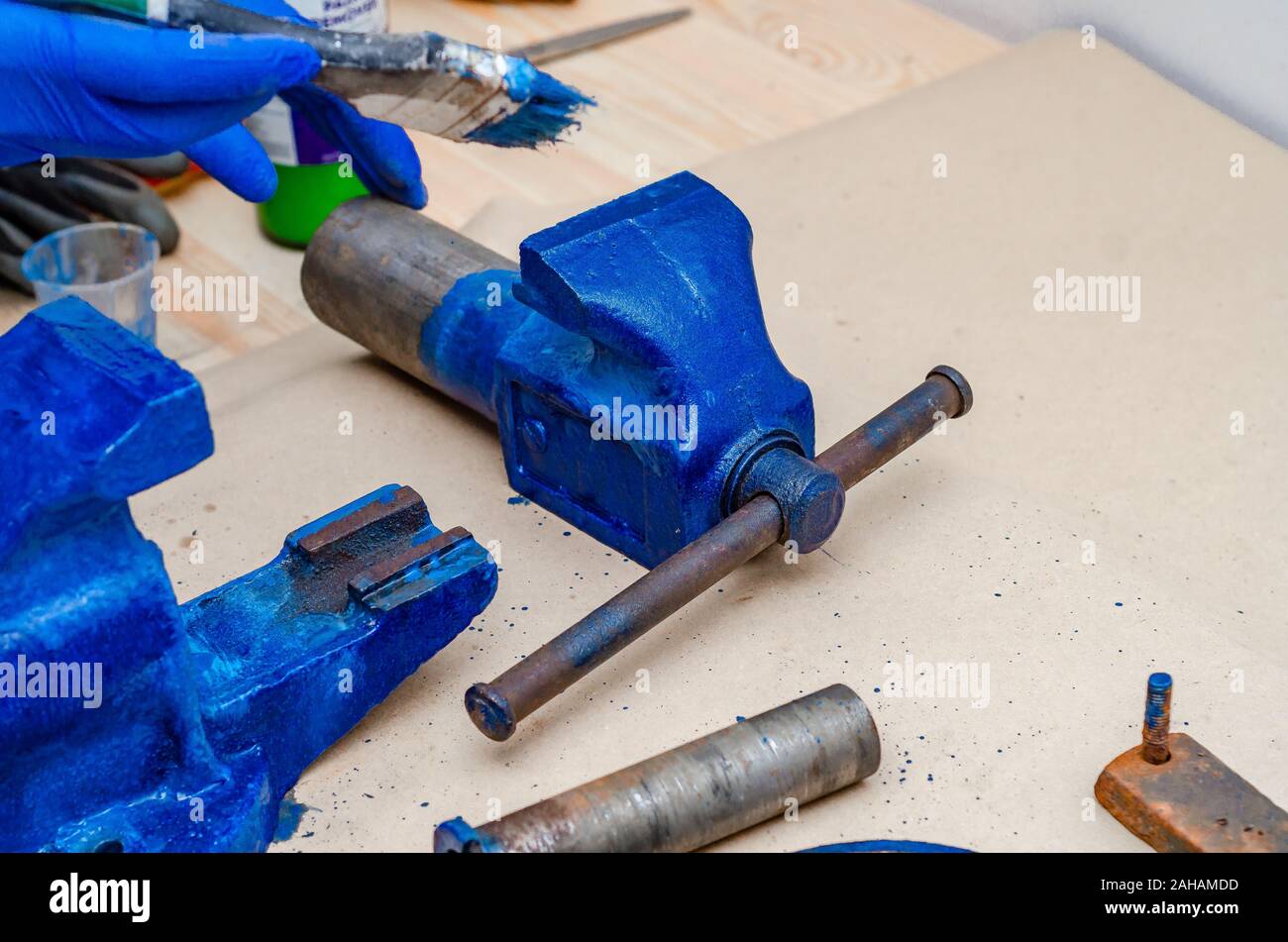 Worker paints a metal vise with blue paint. Stripping old paint Stock