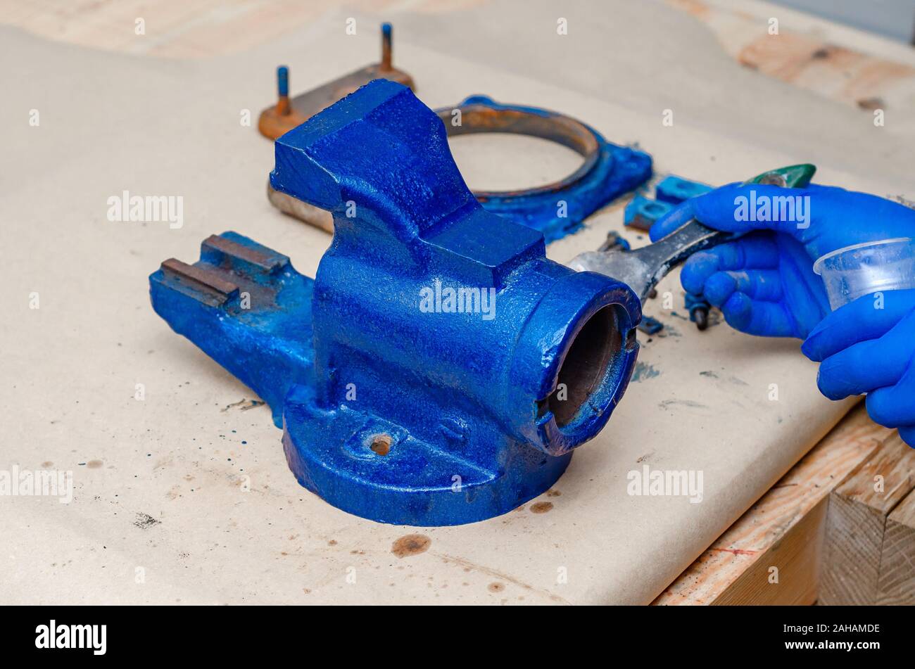 Worker paints a metal vise with blue paint. Stripping old paint Stock