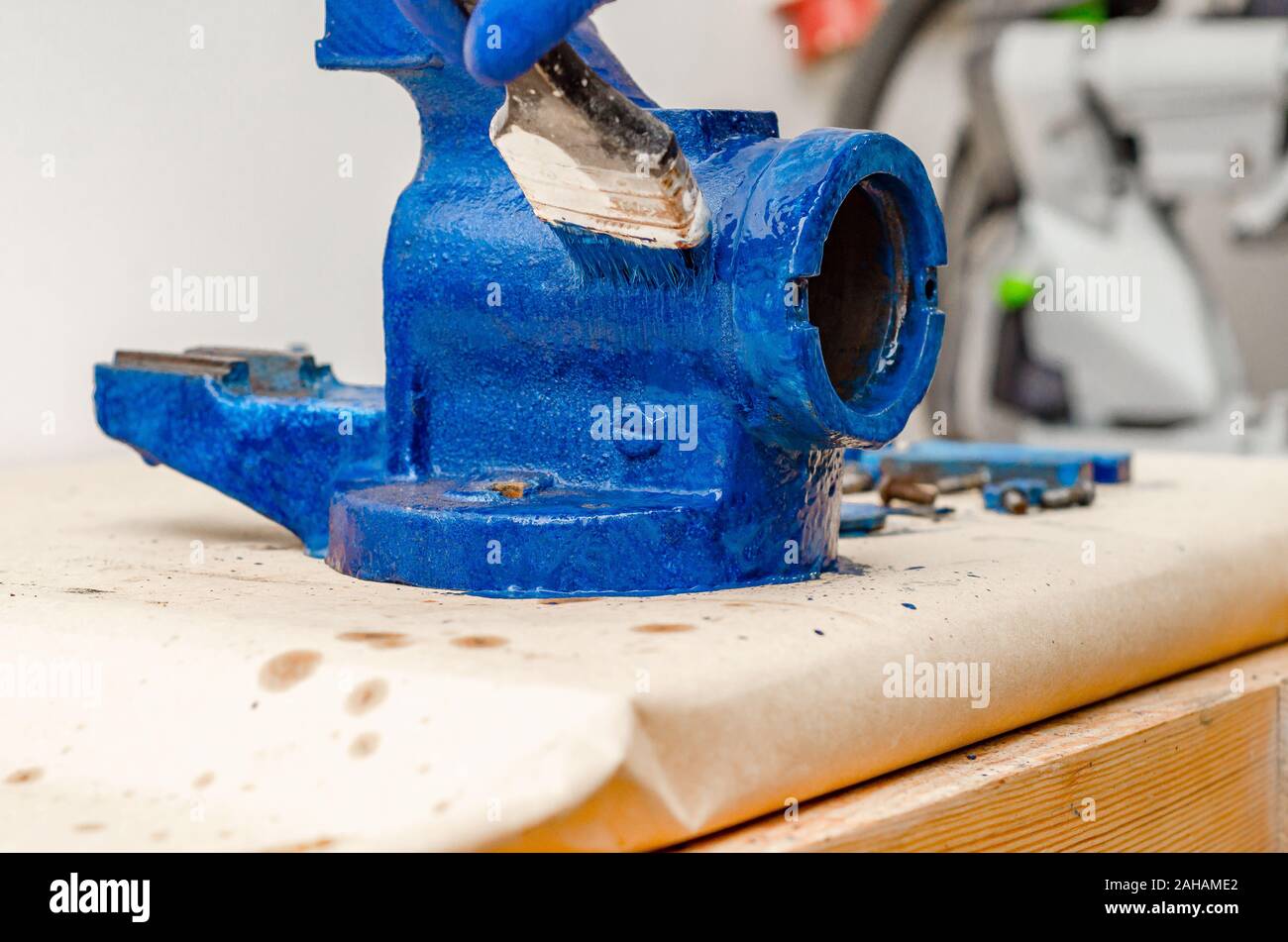 Worker paints a metal vise with blue paint. Stripping old paint Stock