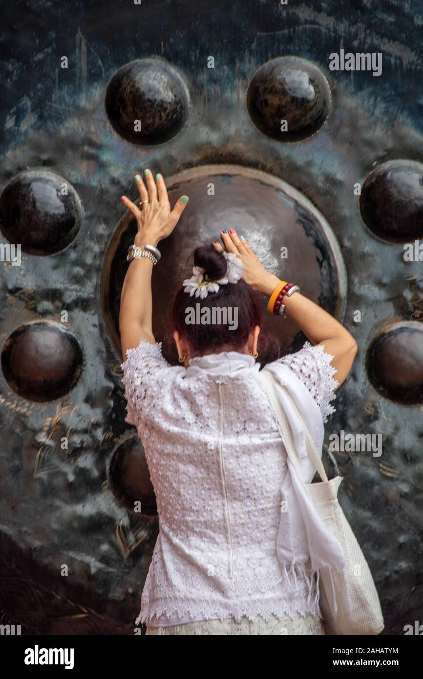 At Kanchanaburi, Thailand- On august 2019 - woman meditating in front of a  gong in the ancient temple at Kanchanaburi called Wat Tam Sua, Thailand Stock Photo