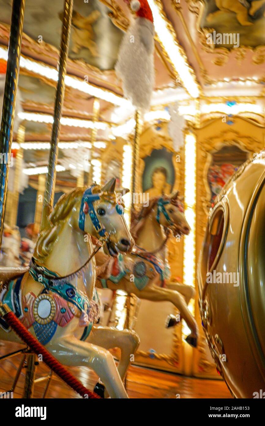 An old-fashioned carousel with white horses and bright lights is illuminated at night in Florence, Italy Stock Photo