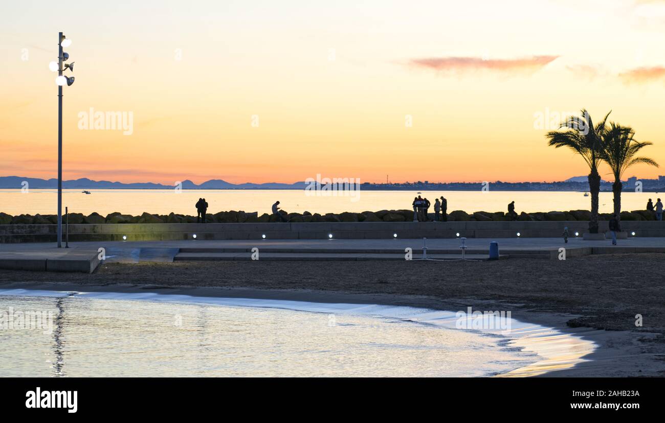 Beach of Torrevieja during sunrise. People walking outdoors enjoy the view Stock Photo