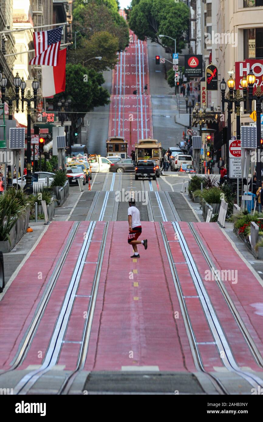 Man running across Powell Street cable car rails in San Francisco, United States of America Stock Photo