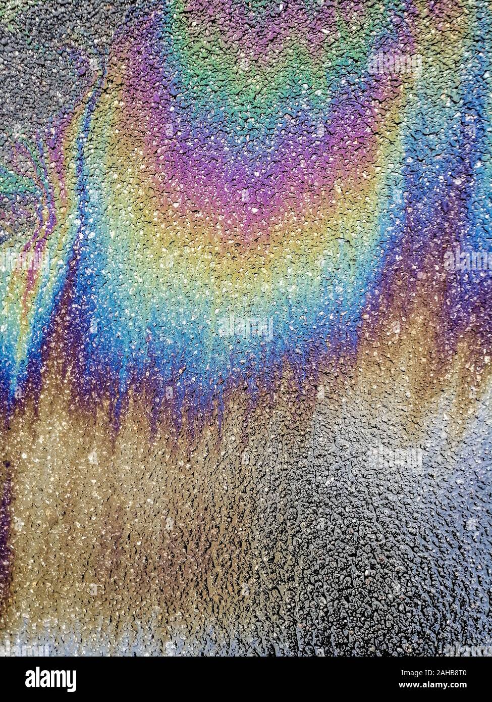 Multi colored oil spill on asphalt road, abstract background Stock