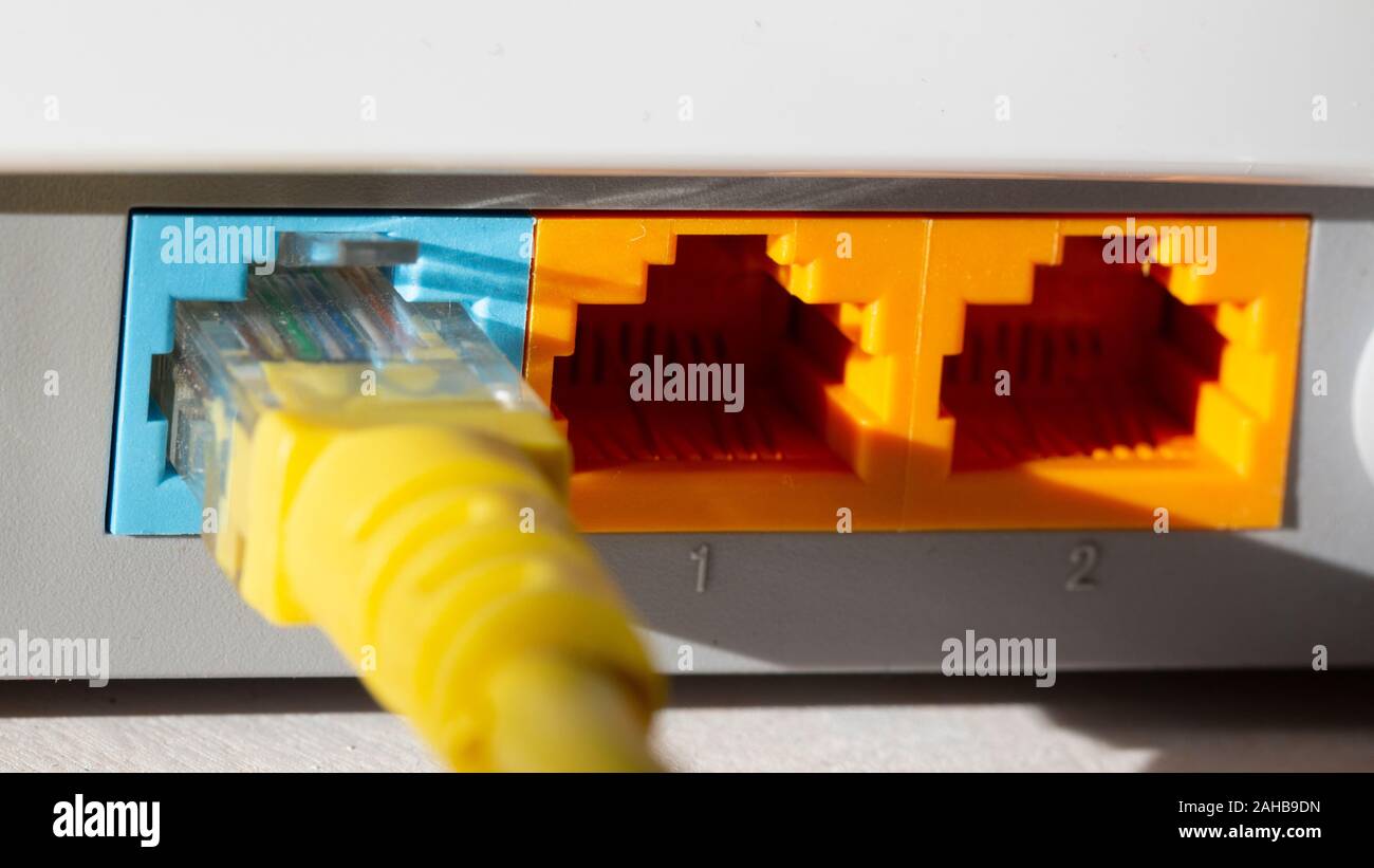yellow internet cable in blue on the back of the network router Stock Photo