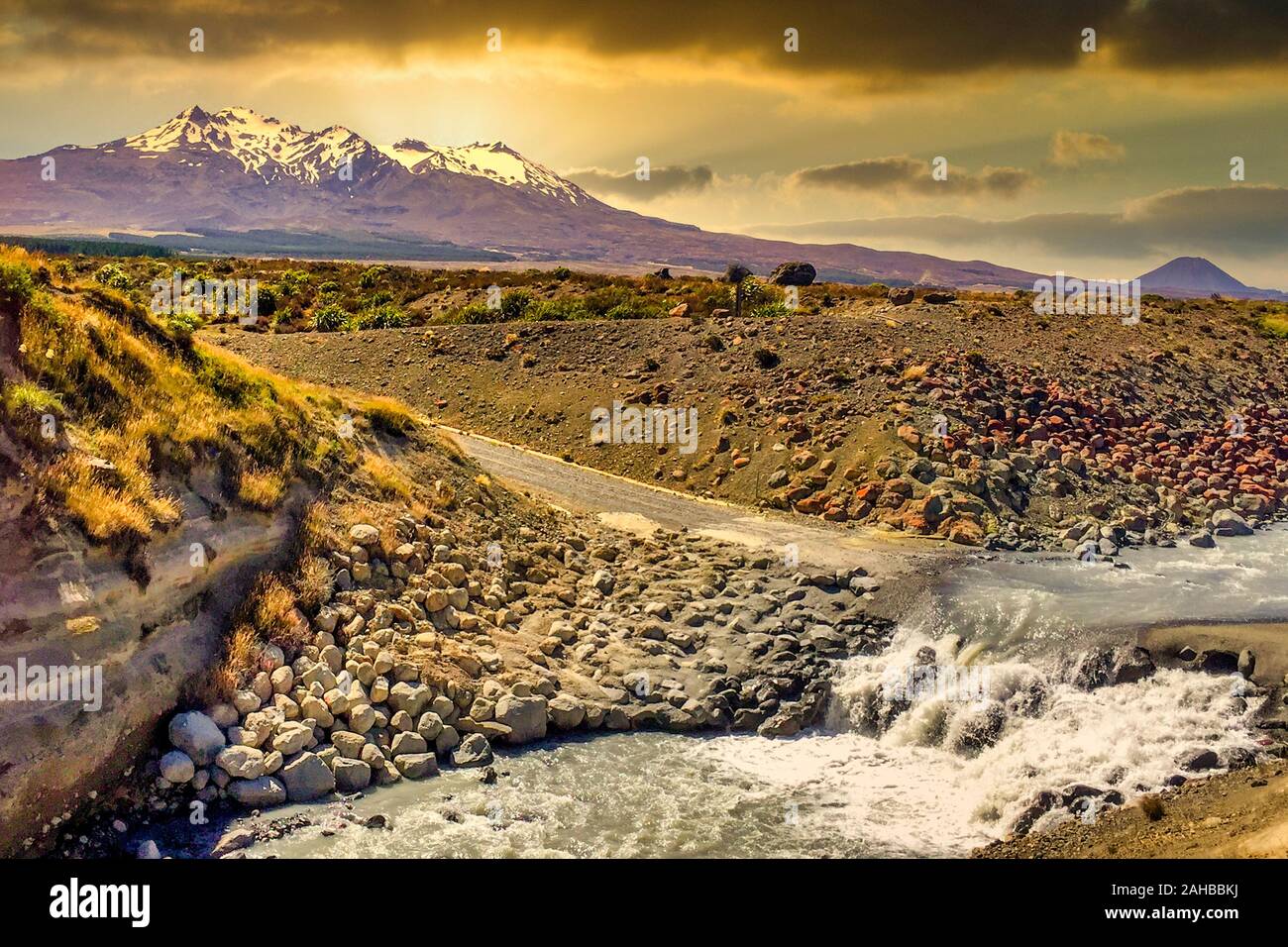 Sunset travelling off road  in the Desert Road in the central plateau of new zealand cross the river heading for the snow capped volcano Stock Photo
