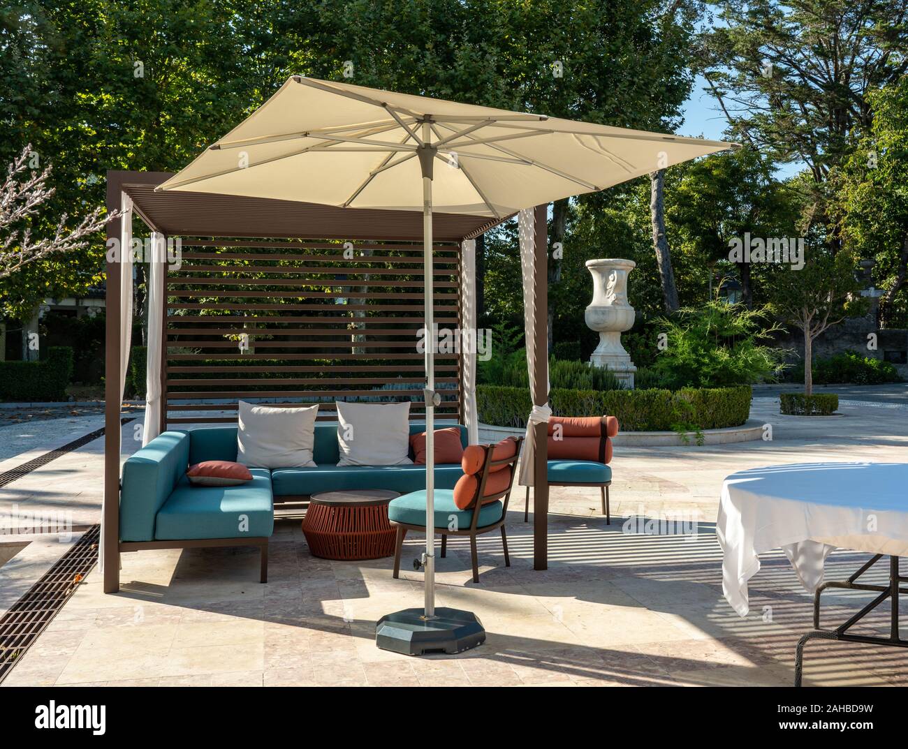 Modern outdoor furniture with umbrella on paved marble patio or courtyard Stock Photo