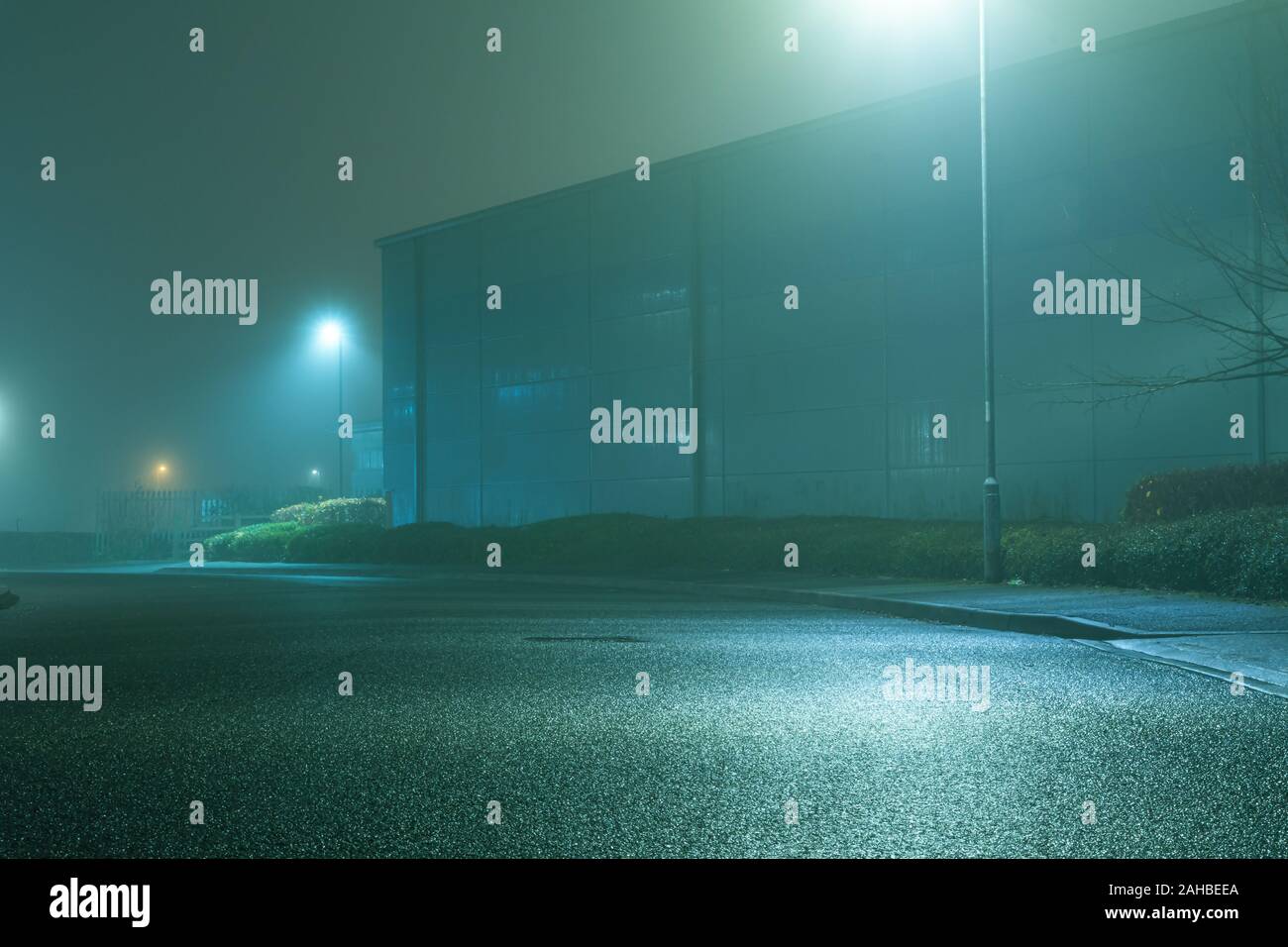 A road and light industrial units, on a foggy, spooky, atmospheric winters night. Stock Photo