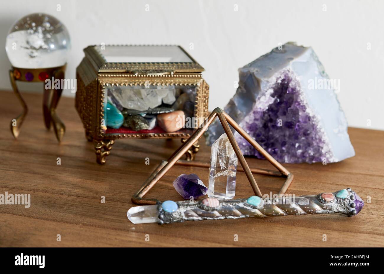 Quartz Crystal Point with amethyst point under a copper pyramid with a healing wand and crystal ball and shallow depth of field Stock Photo