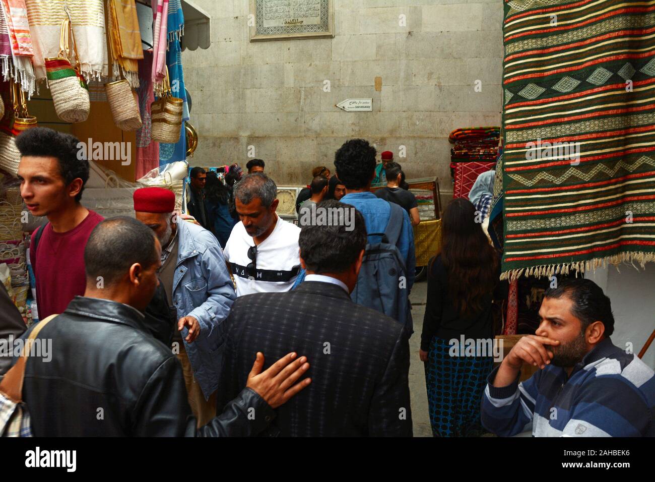 A crowd of local Tunisians walk past souvenir shops in the souk of the Kasbah district of the Medina (old city) of Tunis, Tunisia. Stock Photo