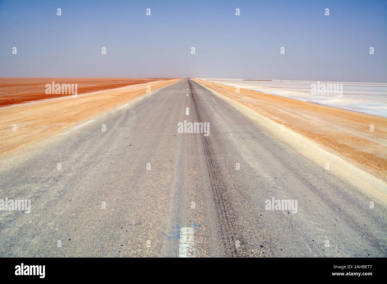 A road running through the colourful Chott el Djerid salt lake near the town of Tozeur in the Sahara Desert of southern Tunisia, North Africa. Stock Photo