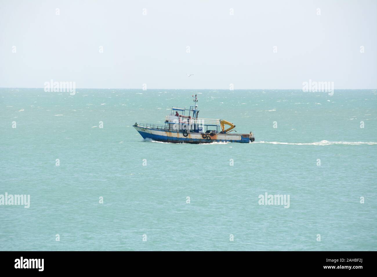 A small Tunisian commercial fishing boat heads out to sea from the city of Mahdia on the Mediterranean coast of Tunisia. Stock Photo
