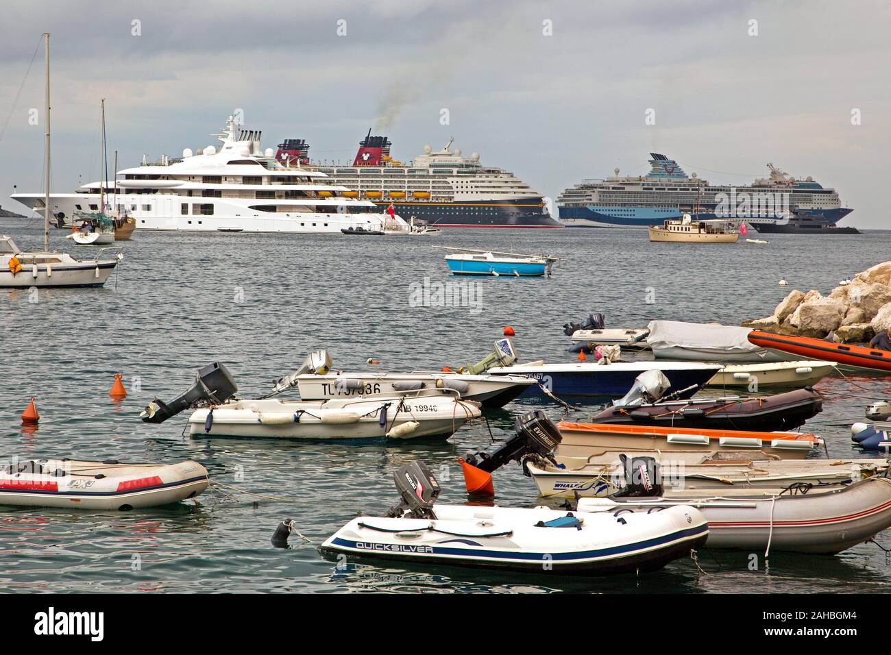 Small zodiacs on the foreshore with private yacht Quantum Blue, Disney Cruise ship Magic and cruise ship Marella Blue in the background in the harbour Stock Photo