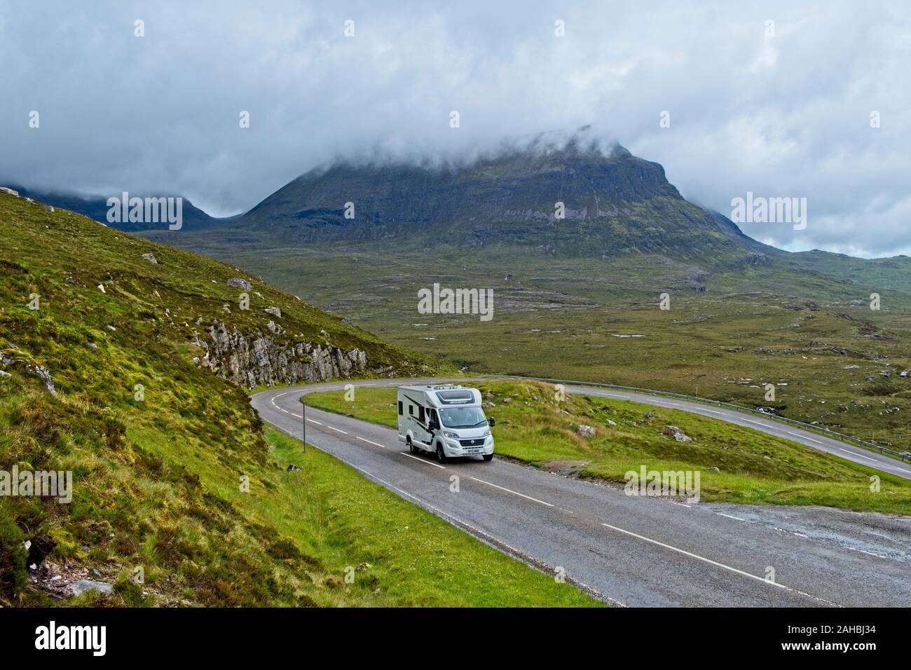 Campervan on a winding road in the Scottish Highlands, with Sail Gharbh capped in low cloud in the background Stock Photo