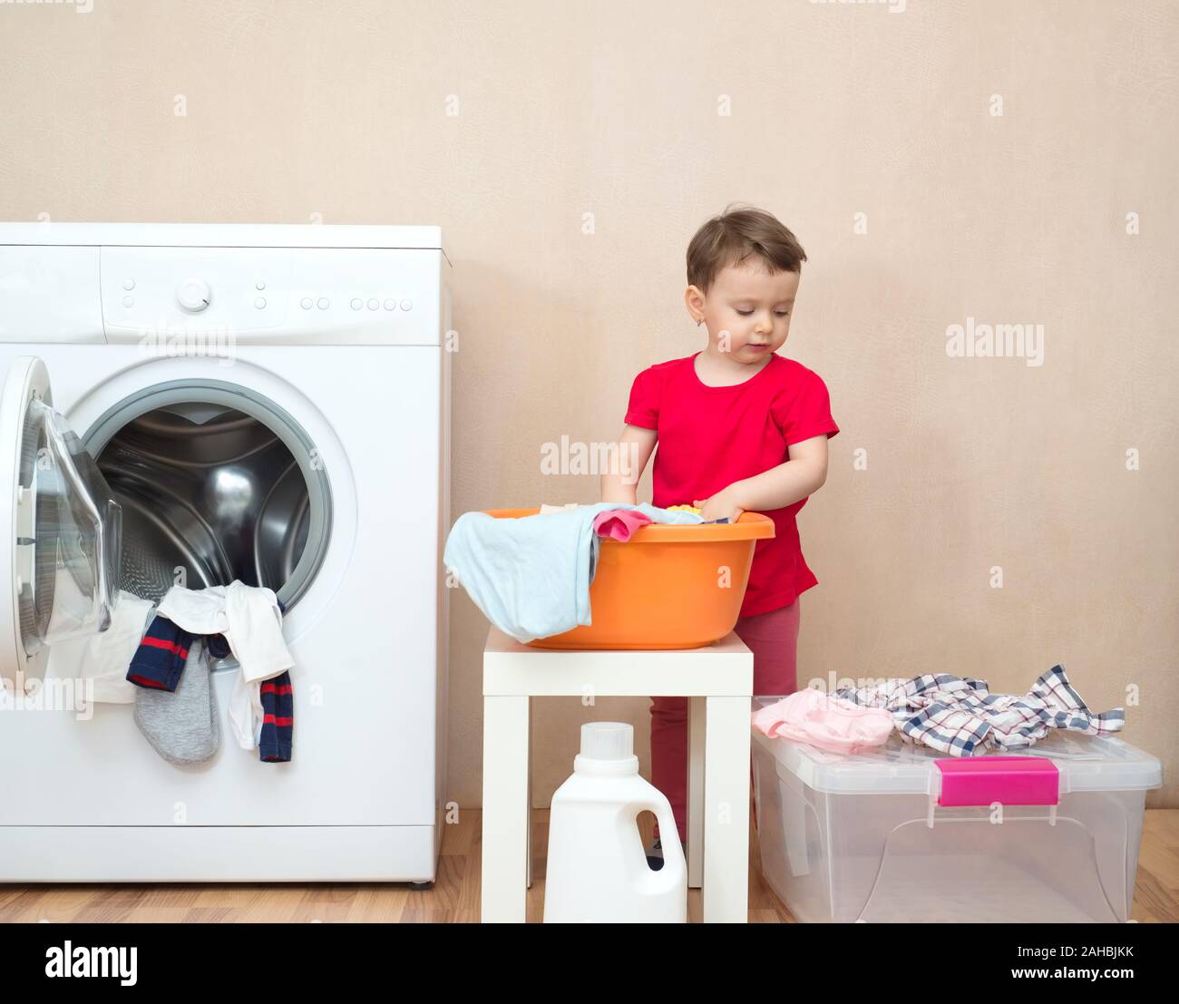 Little girl doing the laundry near a washing machine Stock Photo