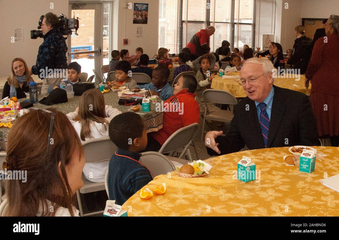 Agriculture Under Secretary Kevin W. Concannon (right) tries a few words of Spanish with Marlon DeBose (green shirt), and other students in this 2nd grade Spanish class seated at this table, in the Elsie Whitlow Stokes Community Freedom Public Charter School, on Wednesday, Feb. 2, 2011.  The school is the first Washington, D.C. school to achieve the Gold Award of Distinction from the HealthierUS School Challenge (HUSSC).  They will now hold the certification and distinction for four years. The goal of the HUSSC is to improve the health of the Nation’s children by promoting healthier school env Stock Photo