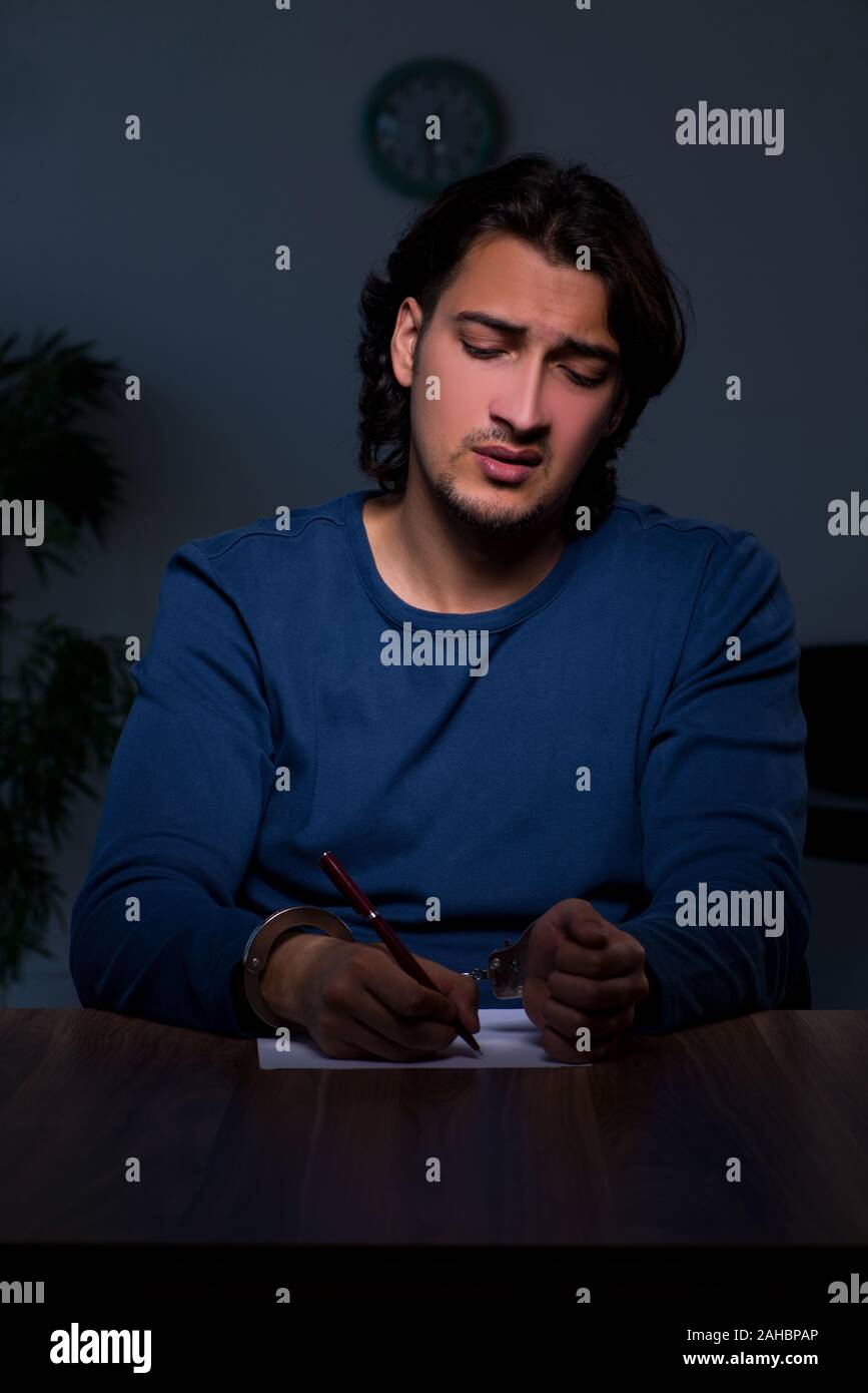 The young convict man sitting in dark room Stock Photo