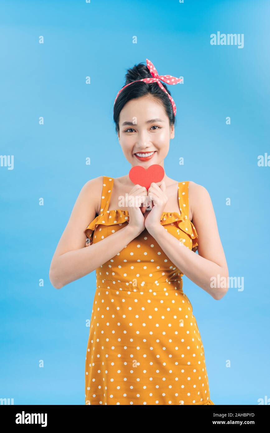 Young woman in casual dress posing with red heart isolated on blue background Stock Photo