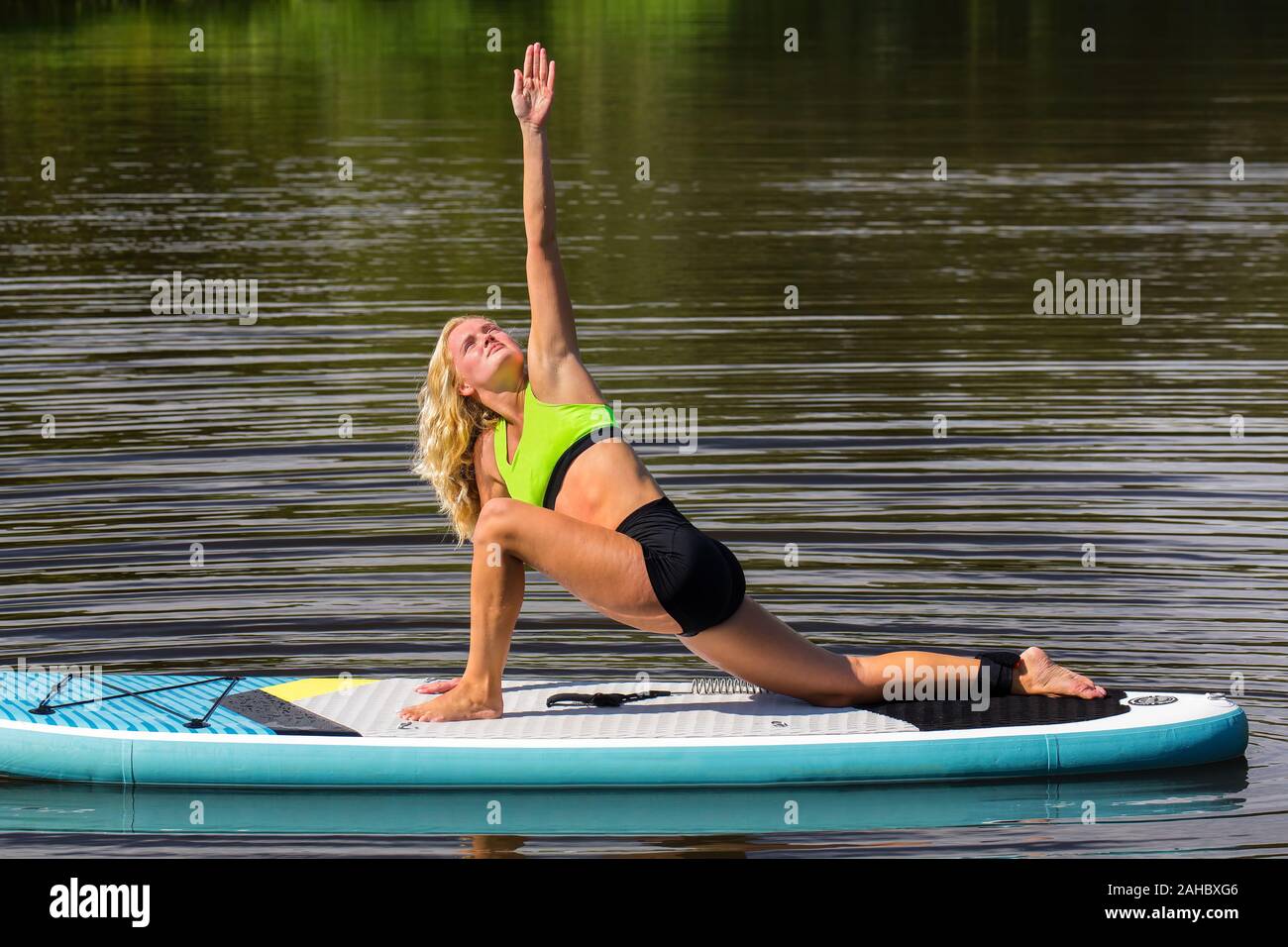 Young european woman in triangle pose on floating paddle board Stock Photo