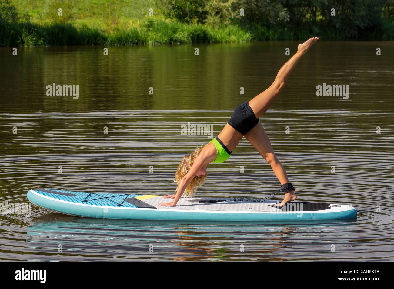 Young european woman training yoga on SUP in lake Stock Photo
