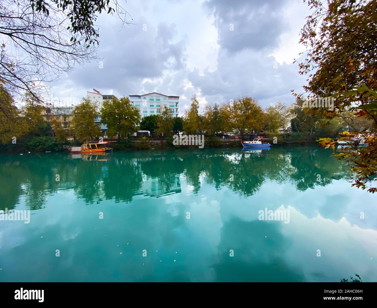 On the lake, a catamaran and boat against the background of houses and trees. Turkey. Autumn. Stock Photo