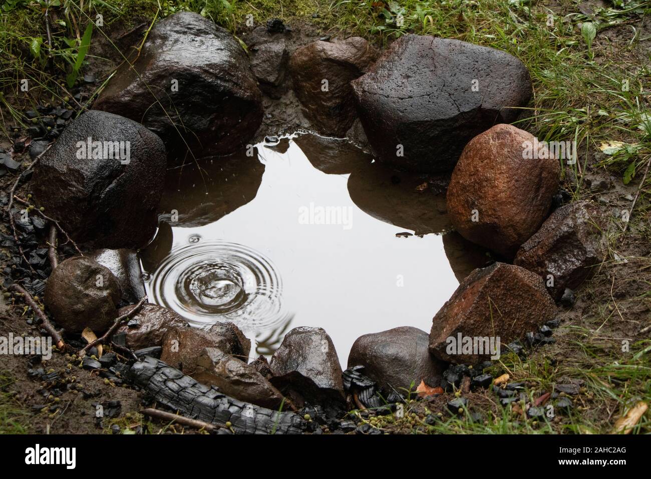 Teardrop and puddle of water in a campfire ring after rain, camping, outdoors Stock Photo