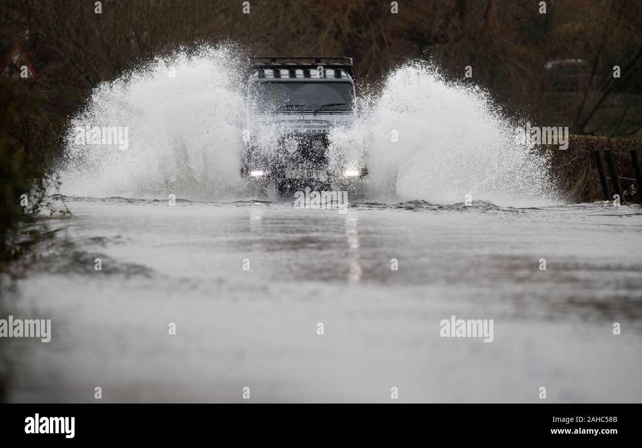 A car makes it's way along a flooded road near to the A338 between Ringwood and Fordingbridge in Hampshire. Stock Photo