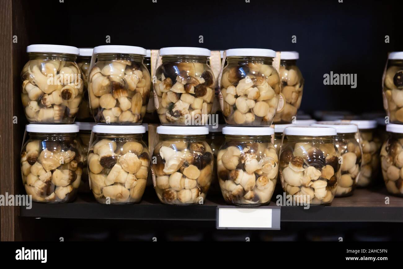 Closed glass jars with popular in Catalonia pickled young fredolics (tricholoma terreum mushrooms) on shelf in store Stock Photo