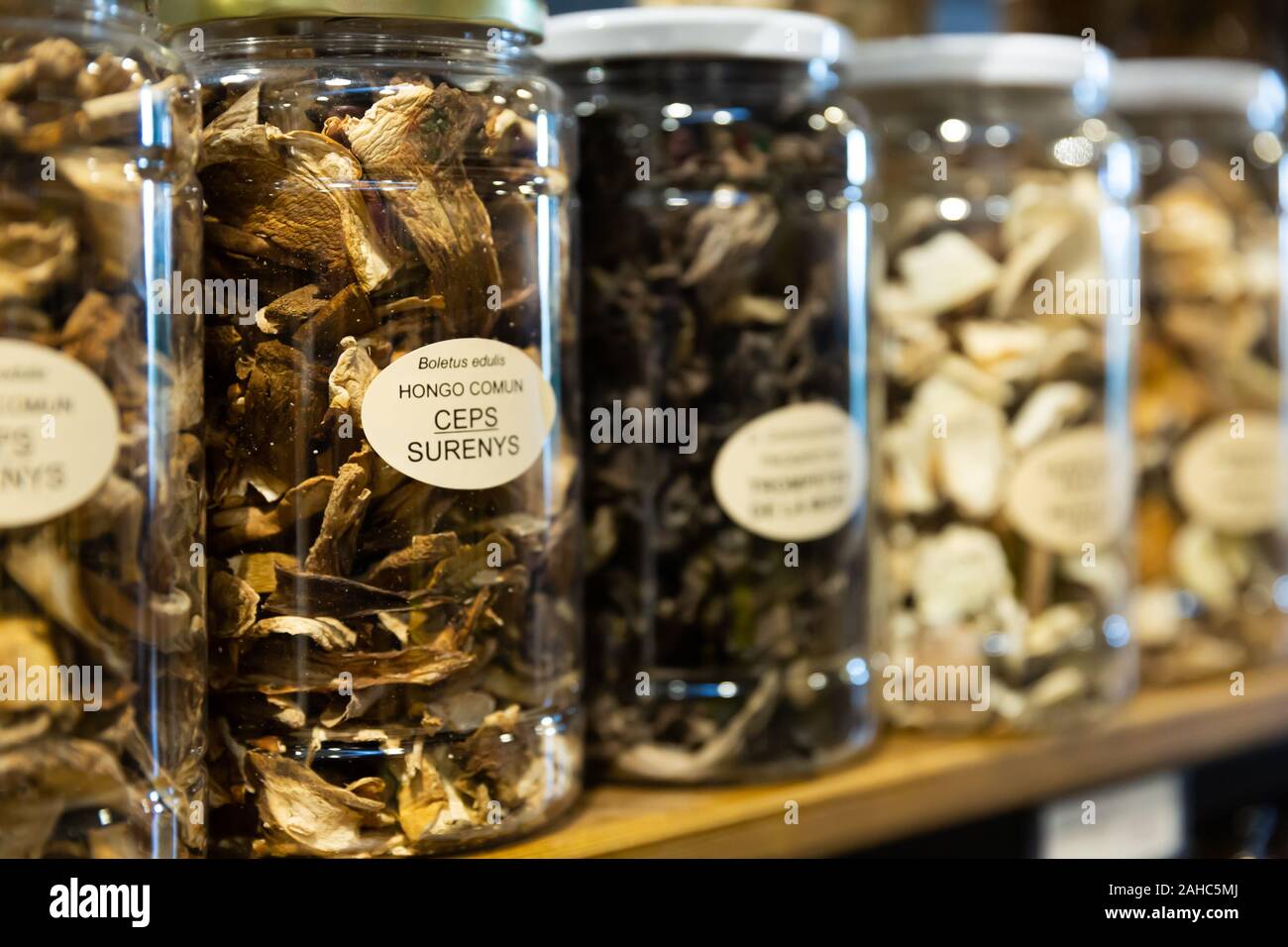 Dried red and black chanterelles, champignons, fairy-ring mushrooms in jars at grocery store counter Stock Photo