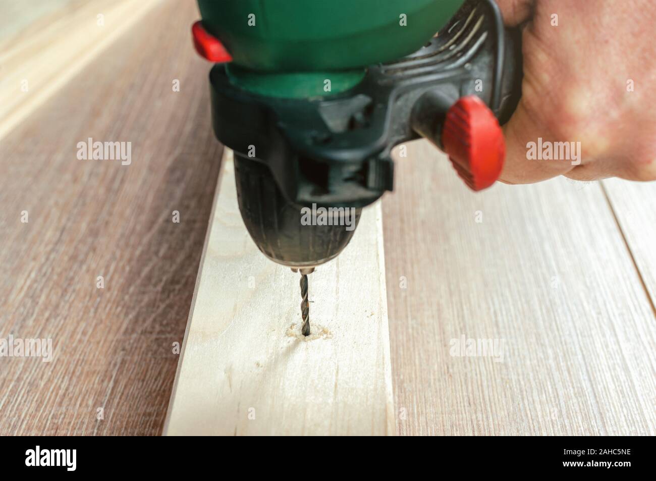 Man making hole into the wood with drill Stock Photo