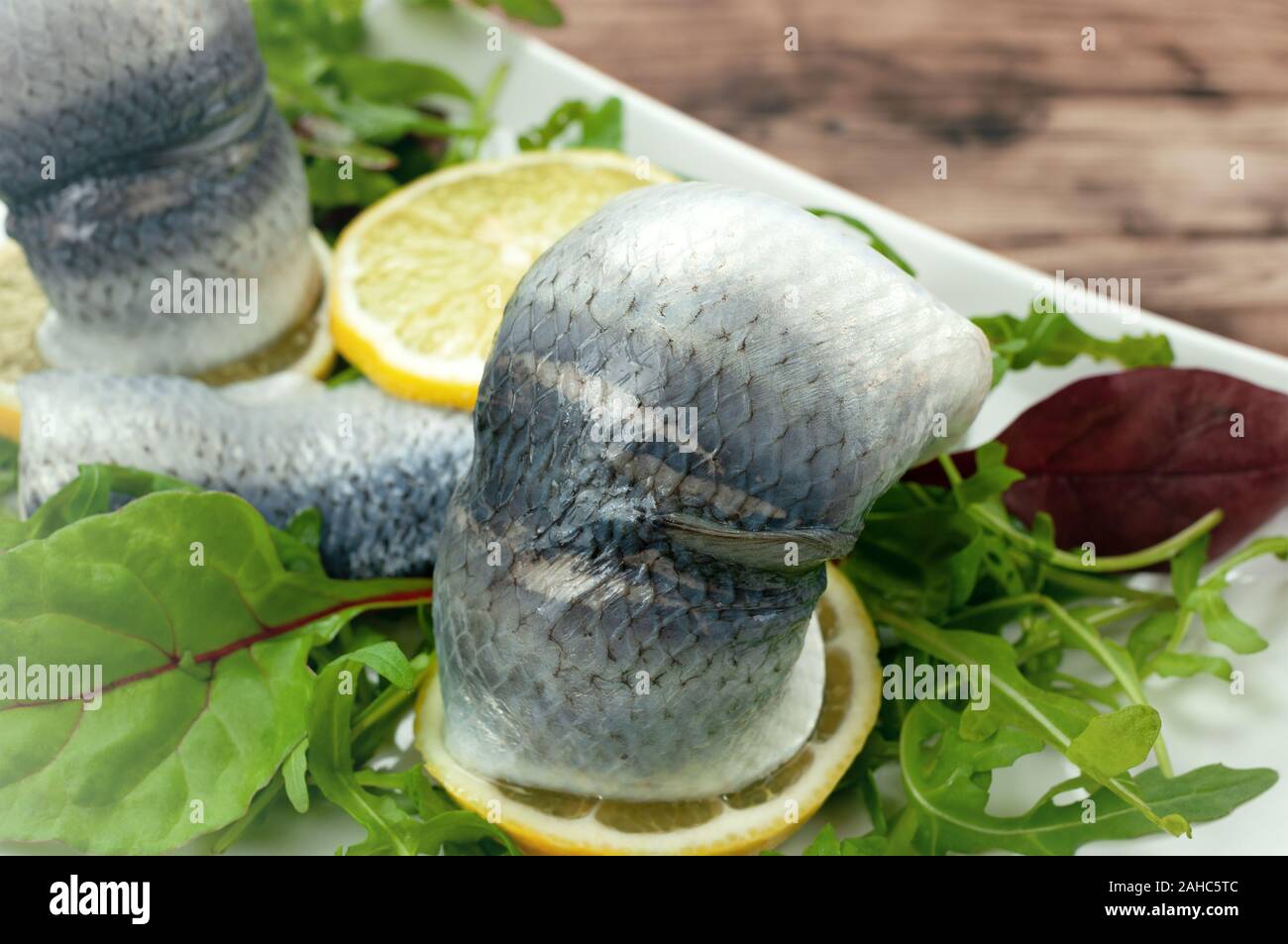 Pickled herring with mixed salad on wooden table Stock Photo