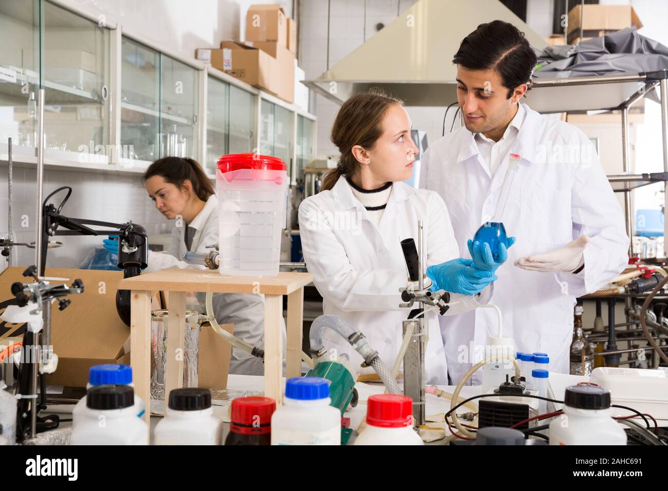 Microchemists Professional chemists working together in laboratory, analyzing liquid ...