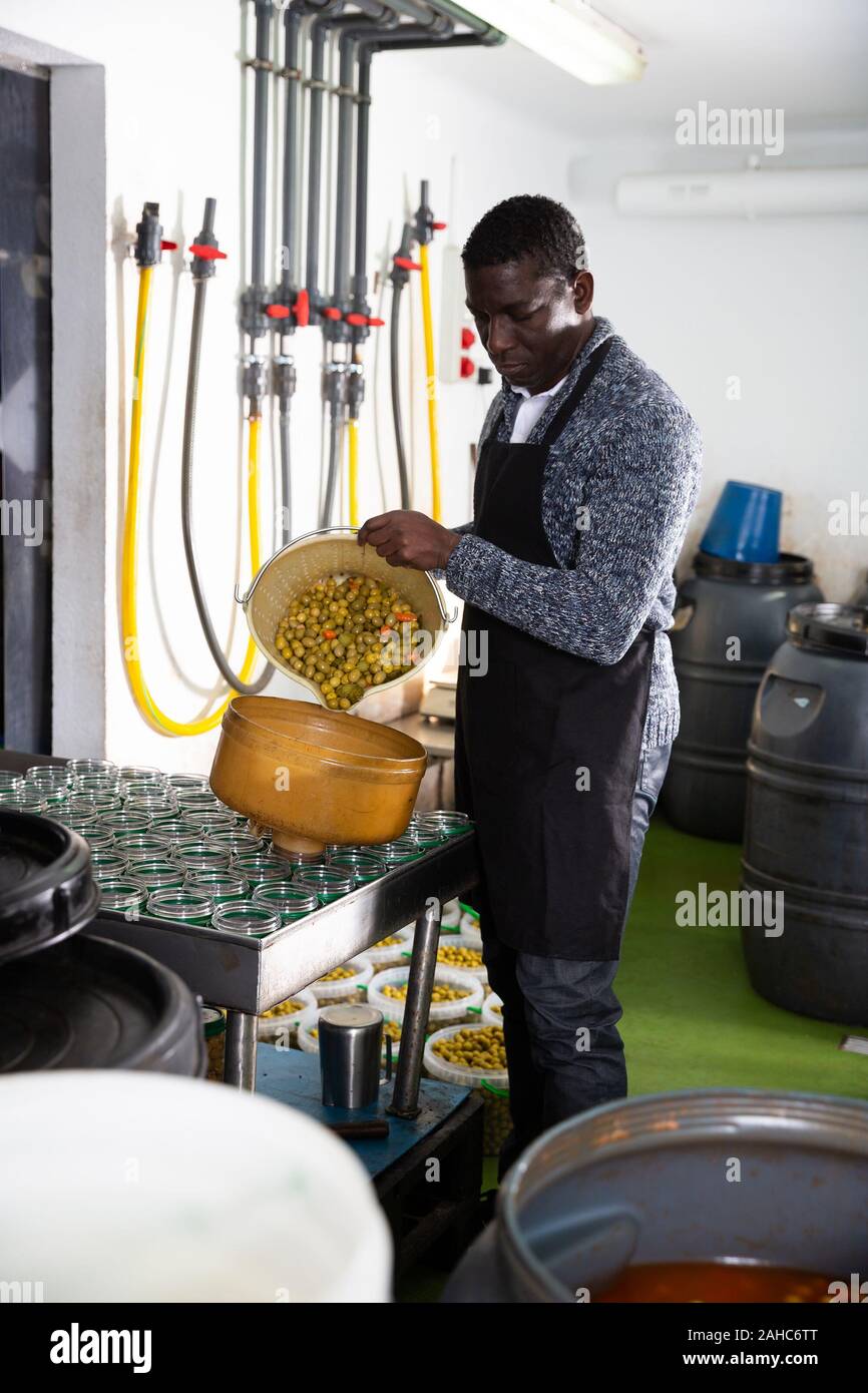 Worker prepares glass jars and olives for canning Stock Photo Alamy