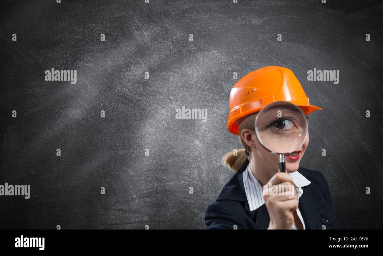 Building inspector looking through magnifying glass. Young construction specialist in safety