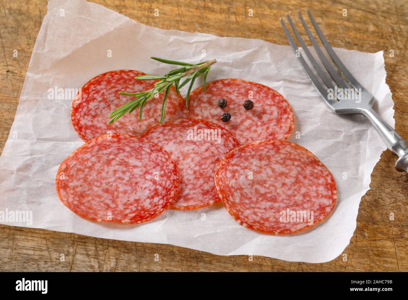 Sliced salami sausage on white wax paper Stock Photo