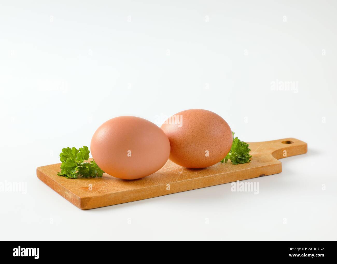 Two brown eggs on wooden cutting board Stock Photo