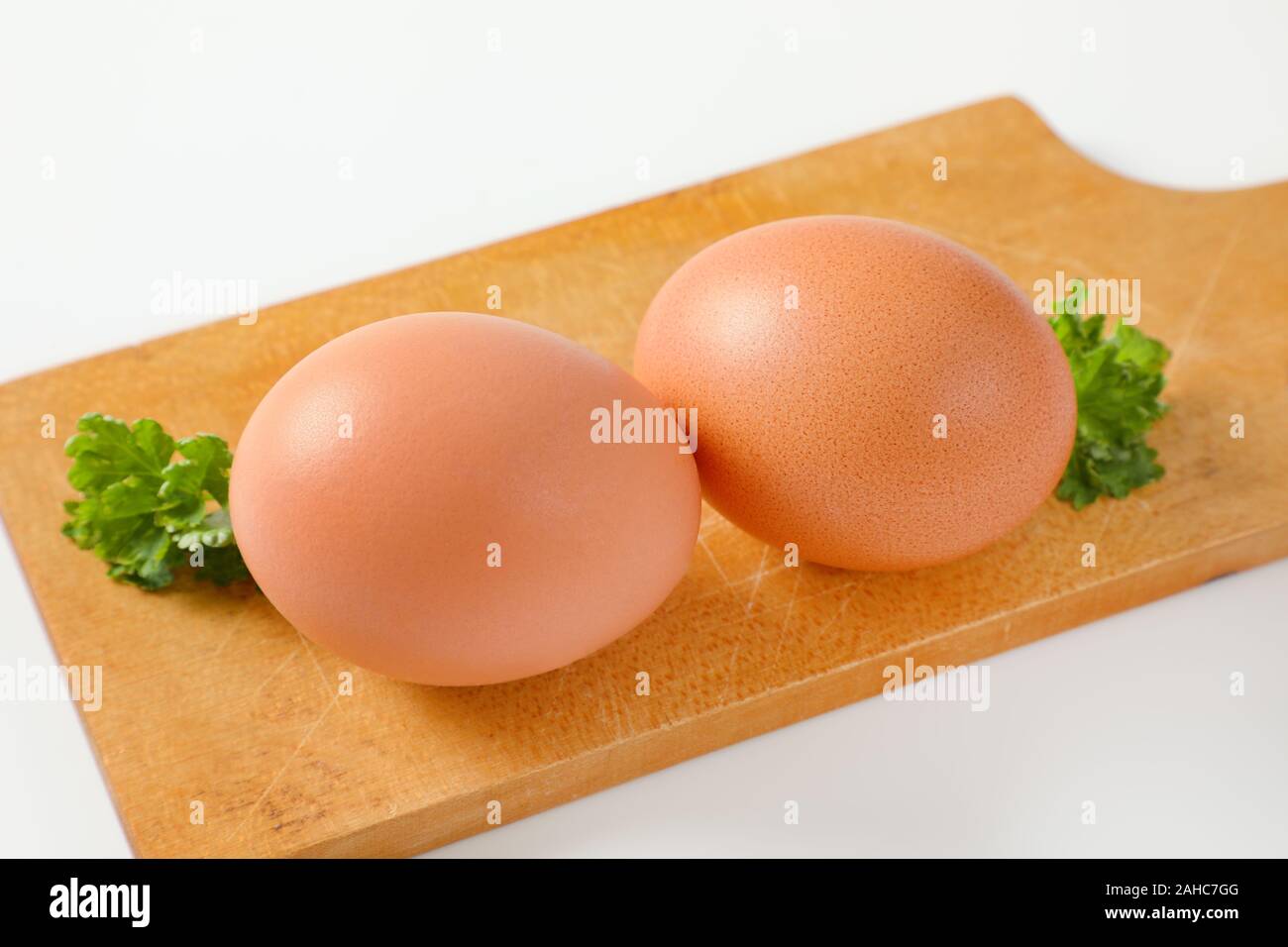 Two brown eggs on wooden cutting board Stock Photo