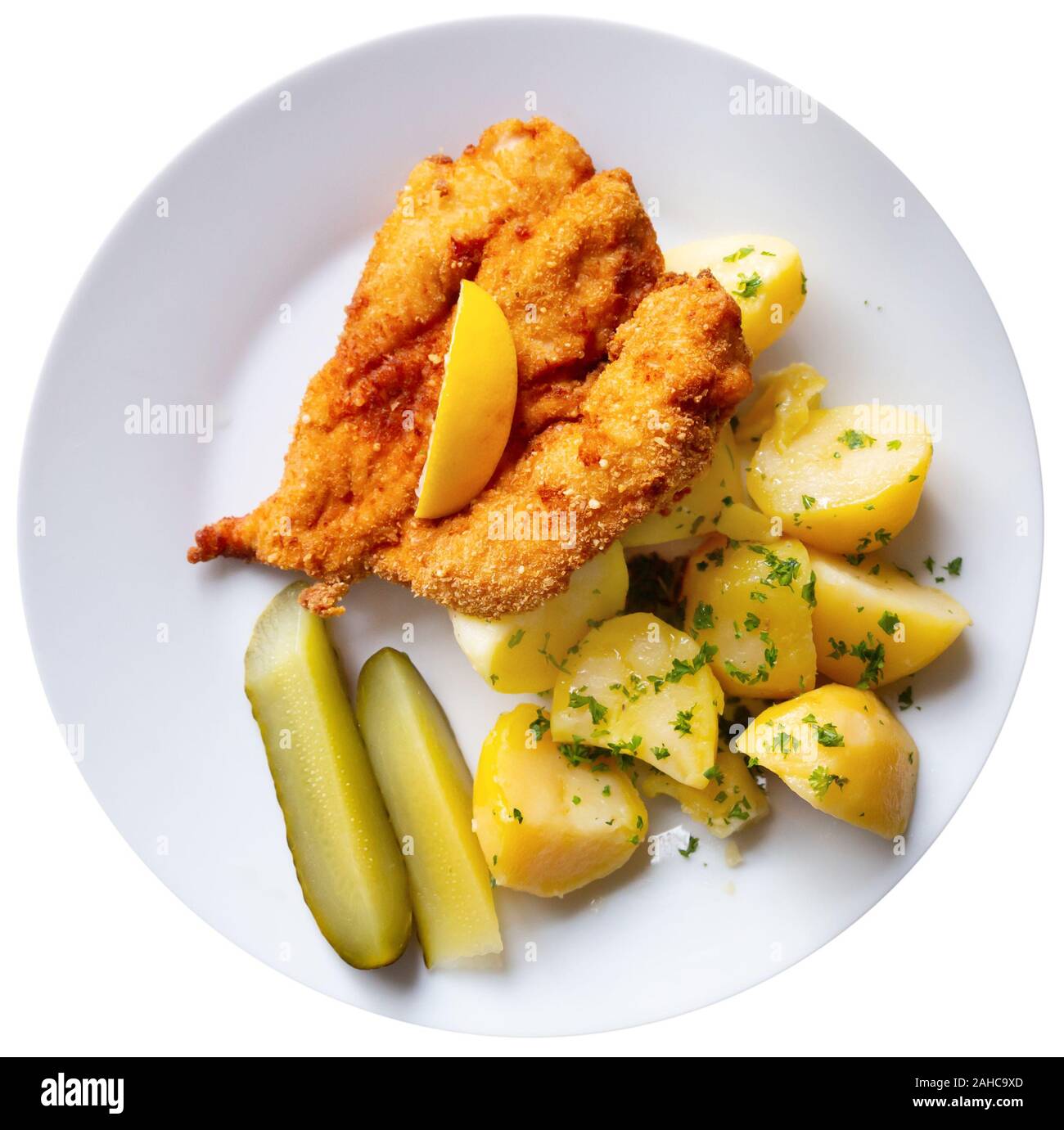 Top view of fried chicken cutlet breaded with Parmesan served with boiled potatoes, greens and pickles. Traditional Czech dish. Isolated over white ba Stock Photo