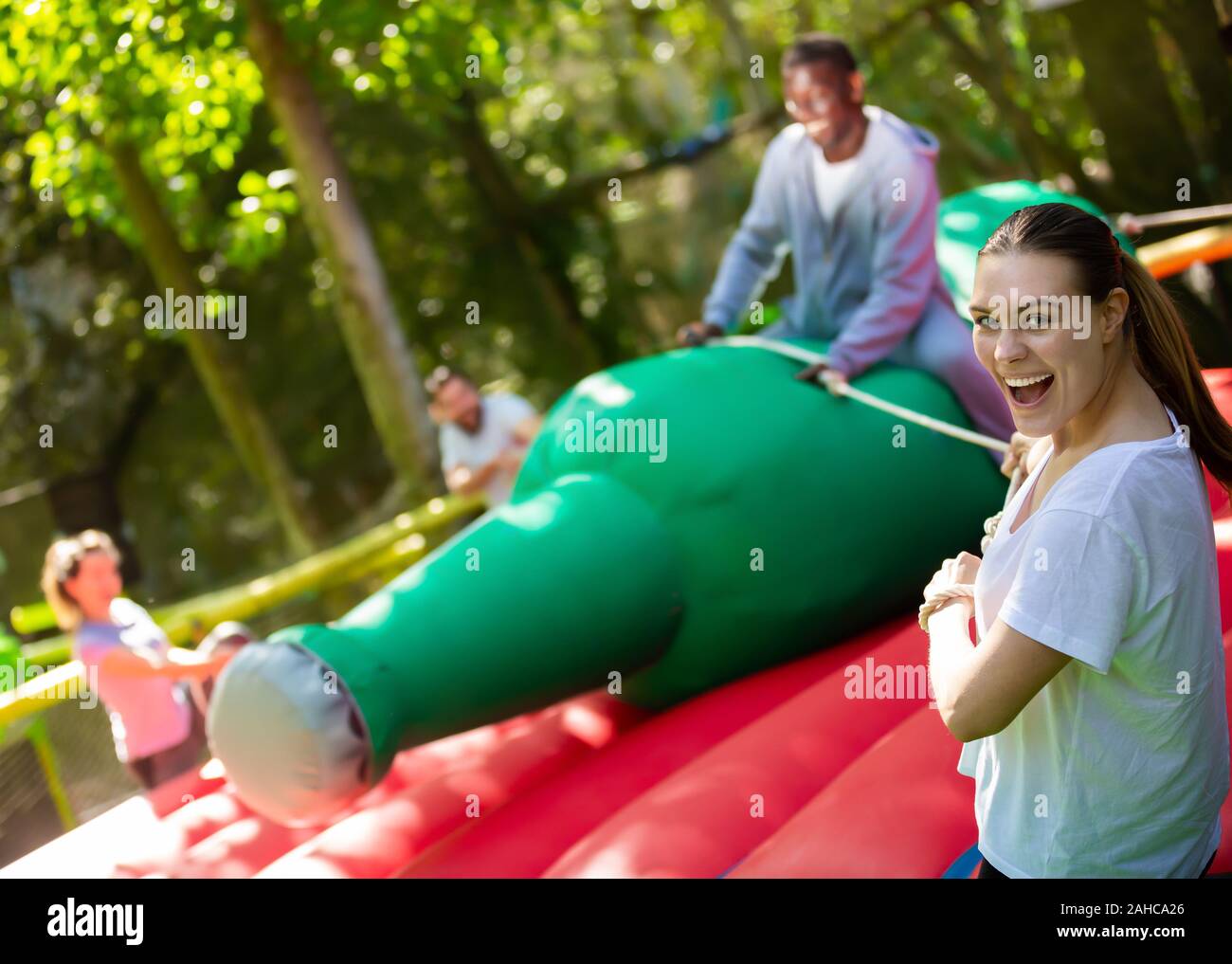 Positive young woman pulling rope of inflatable rodeo bottle, trying to ...
