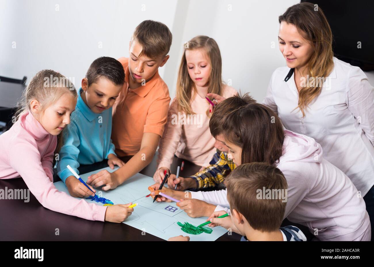 Professor and collective of elementary age children drawing together ...