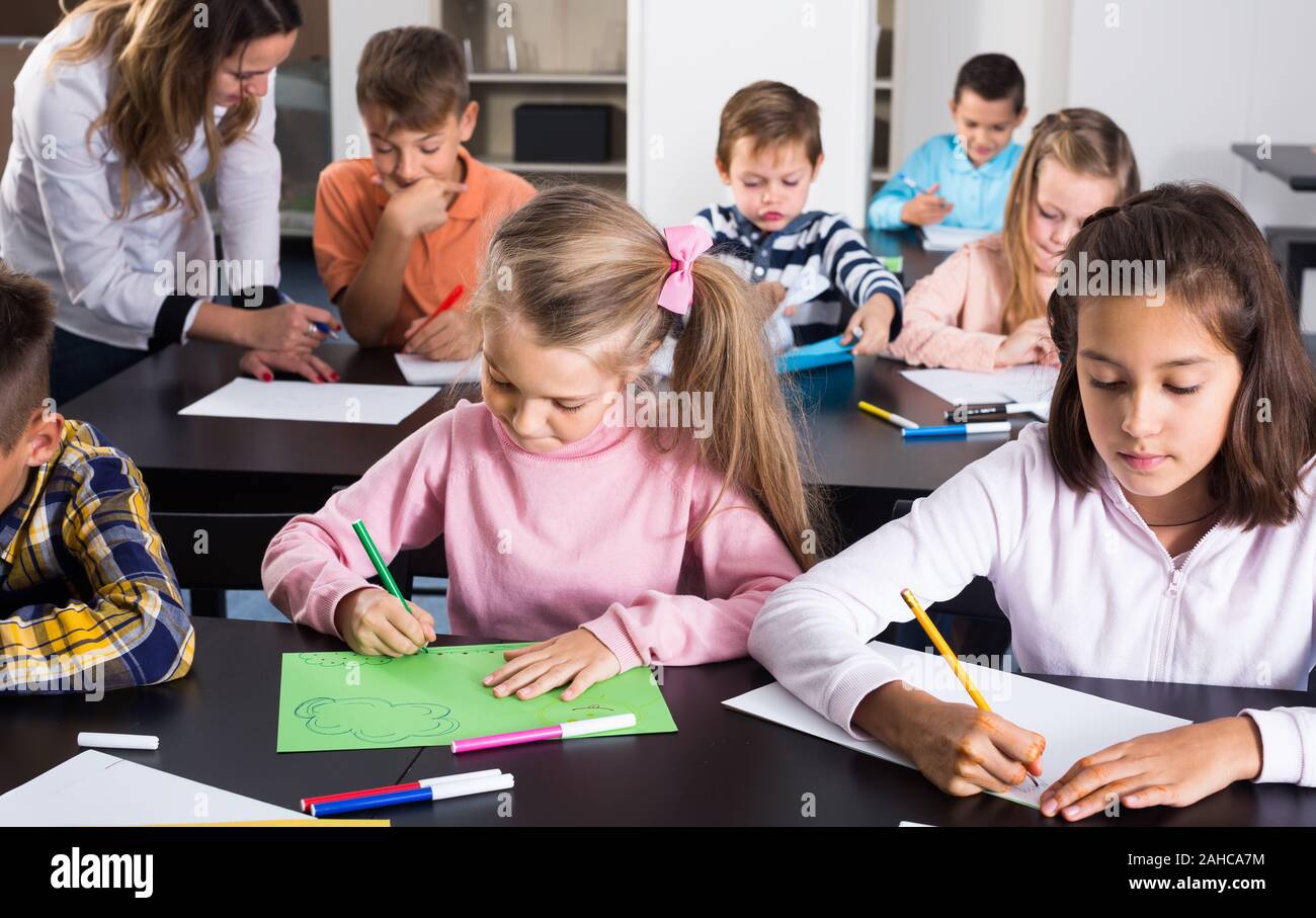 calm little children with teacher drawing in classroom on the lesson Stock Photo