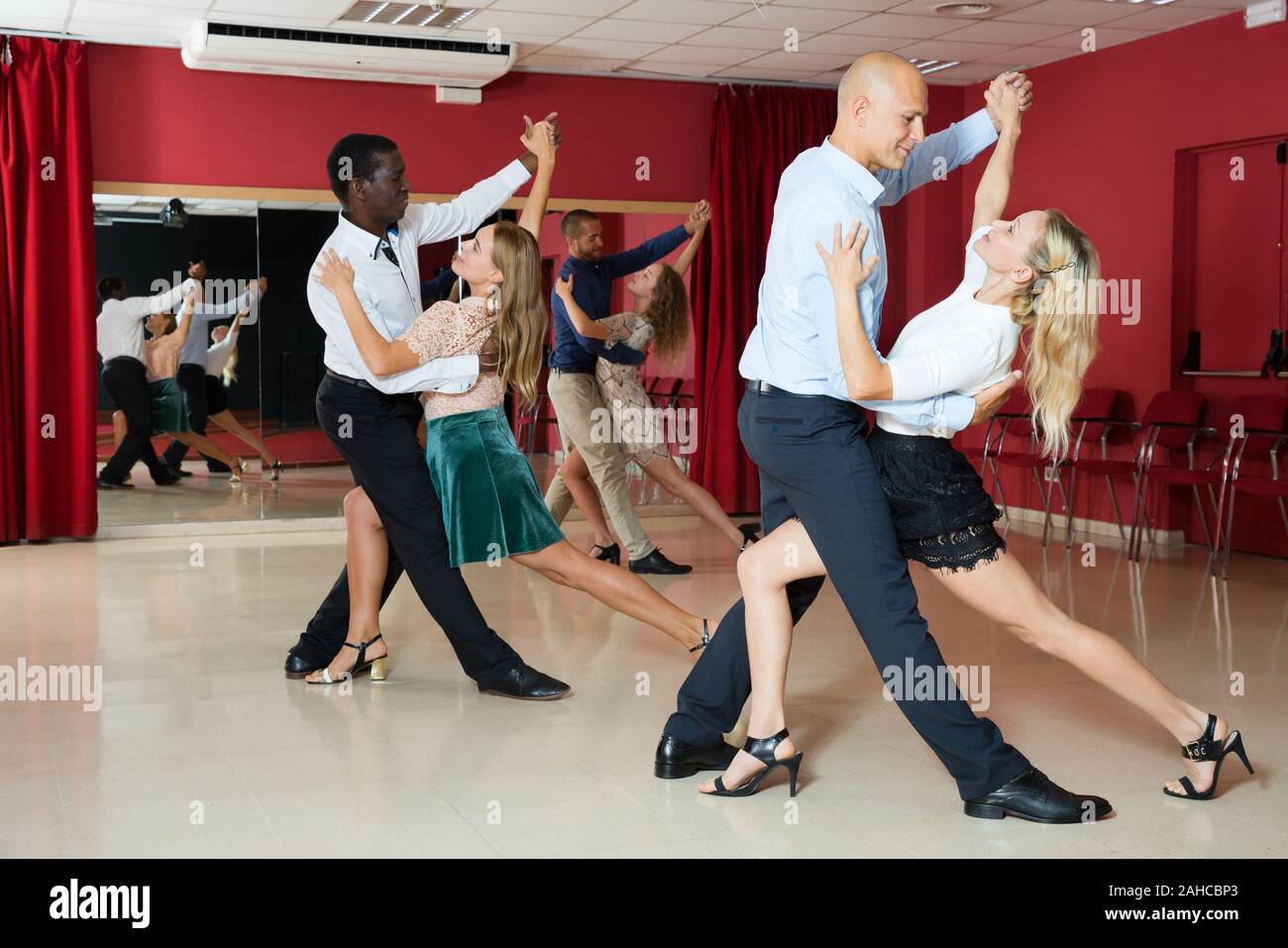 Young smiling people practicing passionate samba in dance class Stock Photo