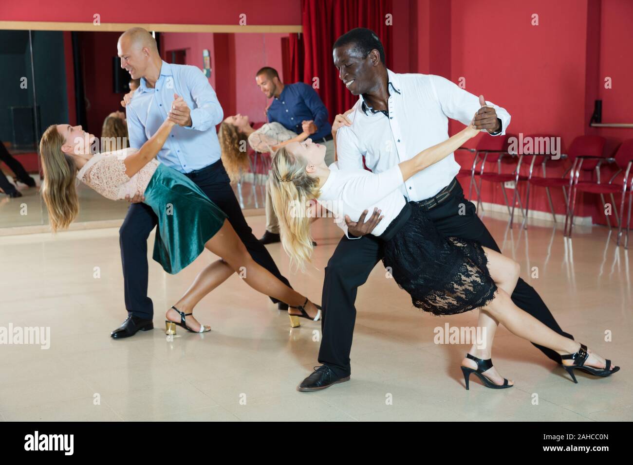 Young smiling people practicing passionate samba in dance class Stock Photo