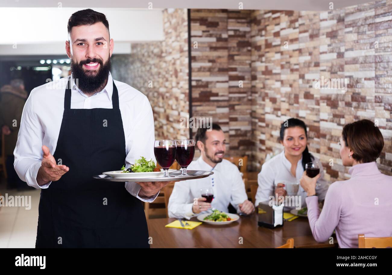 Nice male waiter showing country restaurant to visitors Stock Photo - Alamy