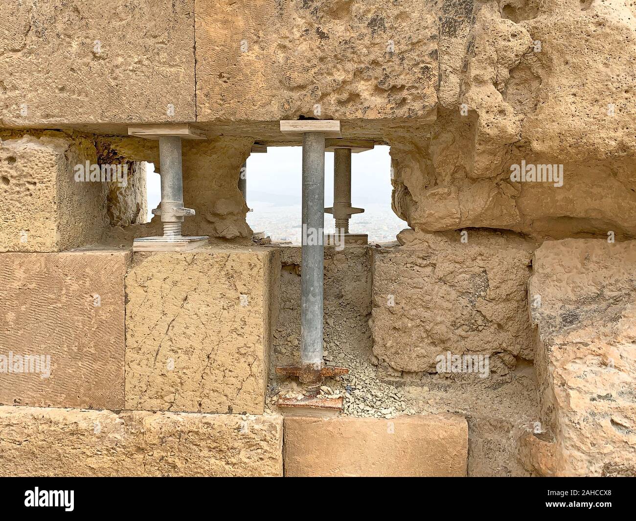 Temporary steel pillars support an ancient stone wall at the Acropolis in Athens, Attica region, Greece, Europe. Provisionally repaired hole in wall. Stock Photo